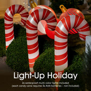 Inflatable candy canes with light-up holiday text on a grassy background